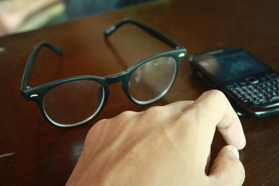 Close-up of hand holding eyeglasses on table