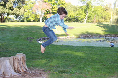 Full length of boy jumping in grass