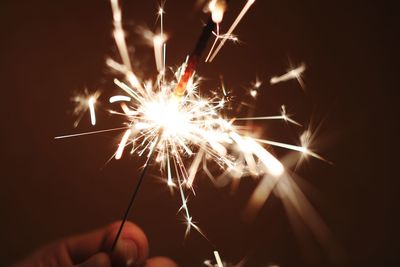 Close-up of hand holding illuminated sparkler at night