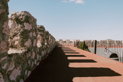 Footpath leading towards buildings against clear sky