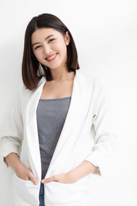 Smiling young woman standing against white background