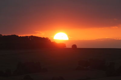 Scenic view of silhouette landscape against orange sky