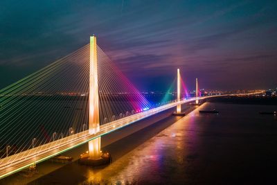 Illuminated bridge over river at night