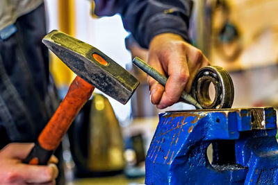 Midsection of male worker hammering metal in factory