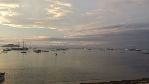 Boats in sea against cloudy sky