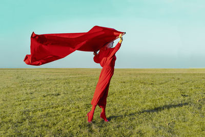 Red umbrella on field against sky