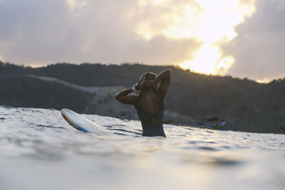 Female surfer in the ocean at sunset