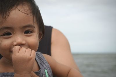 Close-up portrait of cute baby boy against sea