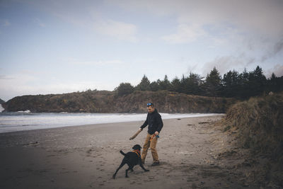 A man is playing with a dog on the californian beach