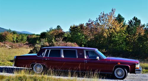 Vintage car on field against clear blue sky