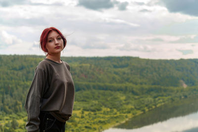Portrait of young woman standing against mountain
