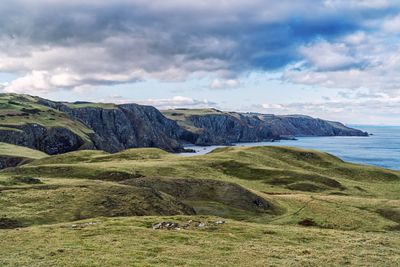 Scenic view of landscape by sea against sky