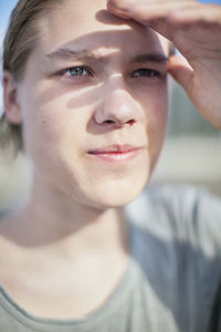 Close-up of young man shielding his eyes from sun