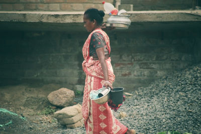 Low angle view of young woman standing against wall