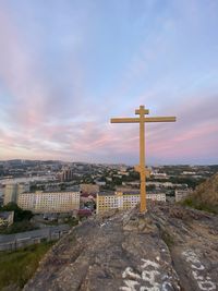 Cross amidst buildings against sky