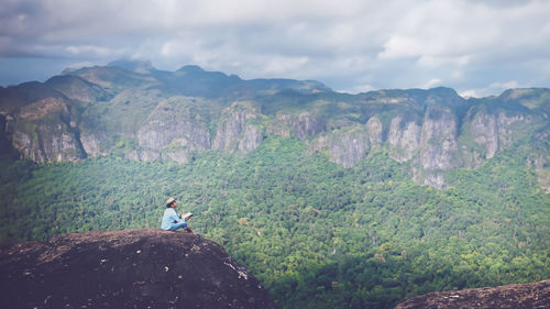 Rear view of man sitting on mountain