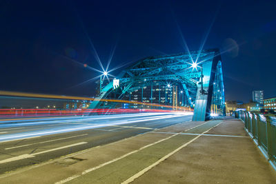 Light trails on bridge in illuminated city at night