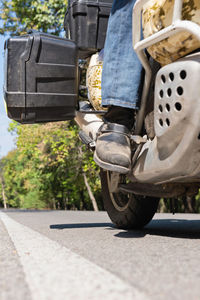 Low section of man riding motorcycle on road