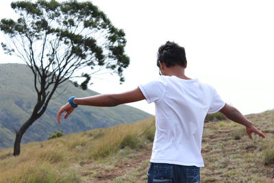 Young man standing on field against sky