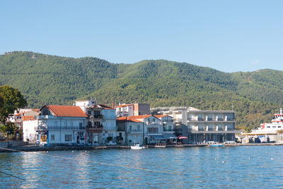 Houses by sea against clear sky