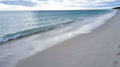 View of calm beach against cloudy sky