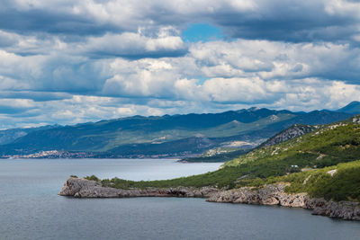 Scenic view of sea and mountains against sky