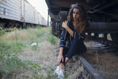 Full length of thoughtful woman sitting at shunting yard