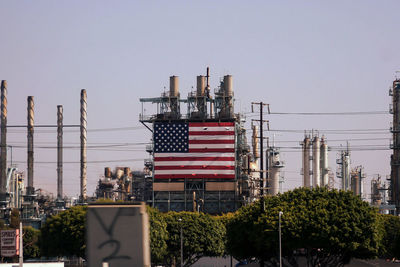 American flag on industry building against clear sky