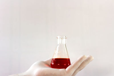 Close-up of hand holding bottle against white background