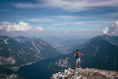 Rear view of man standing on mountain against sky