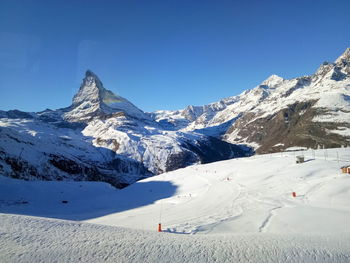 Scenic view of snowcapped mountains against clear blue sky