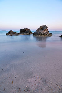 Rocks on beach against clear sky