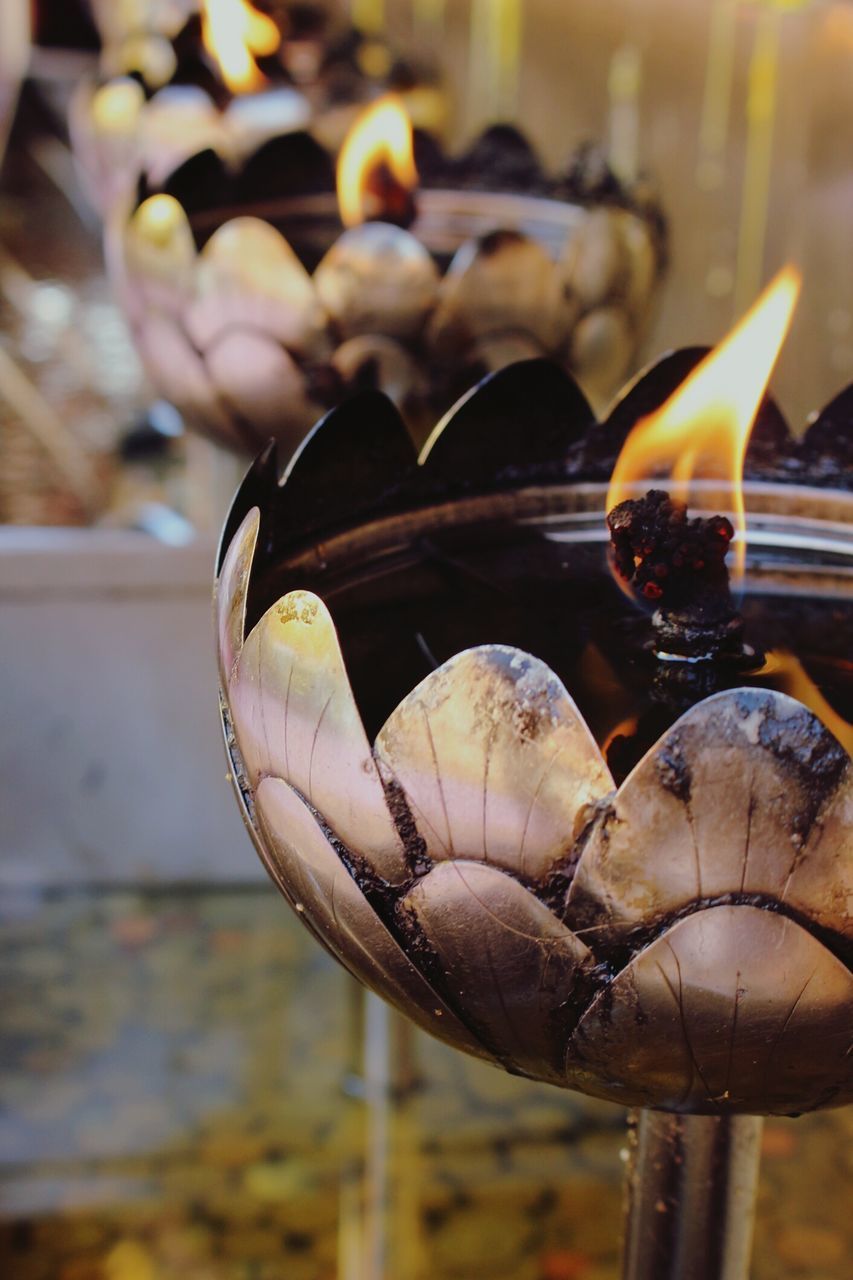 CLOSE-UP OF BURNING CANDLES ON GLASS