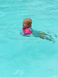 High angle view of girl wearing water wings while swimming in pool