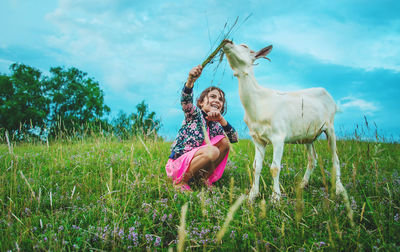 Happy girl feeding grass to goat