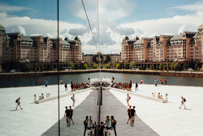 People at lakeshore in city against sky