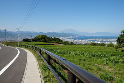 Scenic view of road amidst field against clear sky