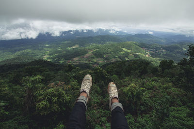 Low section of person on mountain against sky