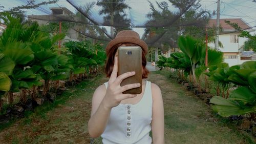 Midsection of woman using mobile phone against plants