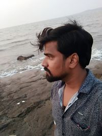 Portrait of young man standing at beach