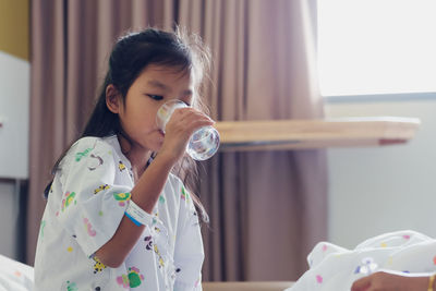 Portrait of young woman drinking water at home