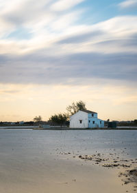 Houses by sea against sky during sunset