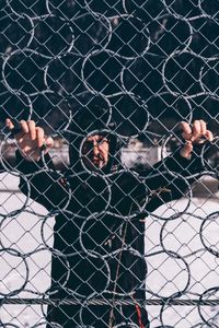 Full length of man seen through chainlink fence