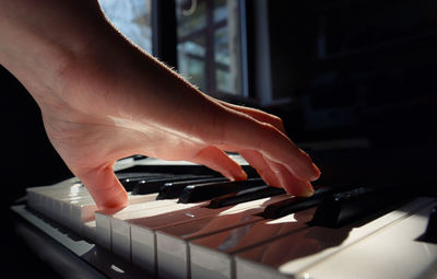 Close-up of cropped hand playing piano