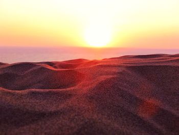 Scenic view of sand dunes against sky during sunset