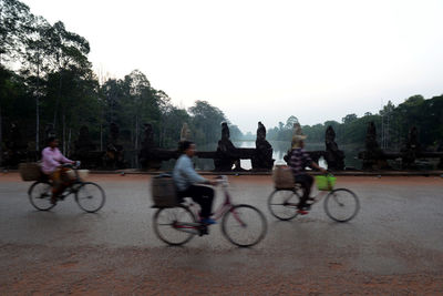 People riding bicycles on road against sky