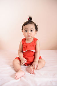 Portrait of cute girl sitting on bed at home