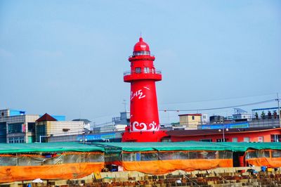 Lighthouse by buildings against sky in city
