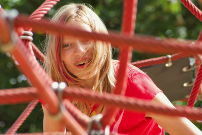 Happy young woman playing on jungle gym 