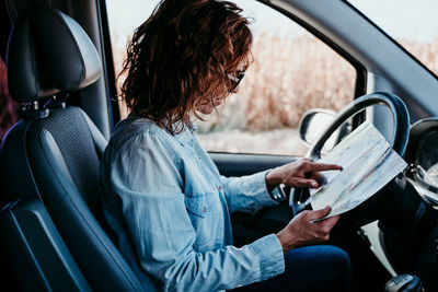 Side view of woman sitting in car